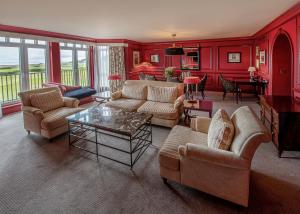 a living room with red walls and couches and a table at Old Course Hotel St Andrews in St. Andrews