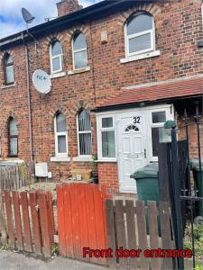 une maison en briques avec une porte blanche et une clôture dans l'établissement Cheerful 2 bedroom mid terrace house in BD2, à Bradford