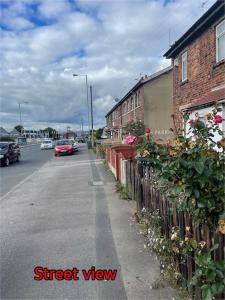 a street view of a street with a fence and flowers at Cheerful 2 bedroom mid terrace house in BD2 in Bradford
