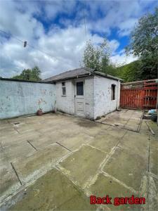 a small white building in a yard with a fence at Cheerful 2 bedroom mid terrace house in BD2 in Bradford