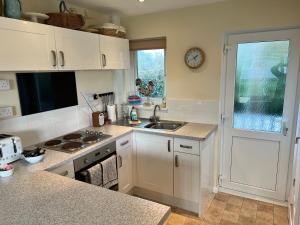 uma cozinha com armários brancos, um lavatório e uma janela em 2 Bedroom Bungalow SV58, Seaview, Isle of Wight Free Wi-Fi em Seaview