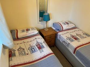 two twin beds in a room with a mirror at 2 Bedroom Bungalow SV58, Seaview, Isle of Wight Free Wi-Fi in Seaview