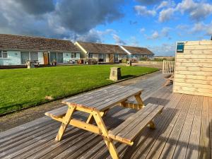 a wooden picnic table sitting on a wooden deck at 2 Bedroom Bungalow SV58, Seaview, Isle of Wight Free Wi-Fi in Seaview