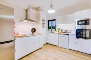uma cozinha com armários brancos e piso de madeira em À dos Reis em Faro