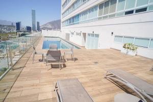 un patio en la azotea con sillas y una piscina en un edificio en Best Apt Luxury Modern New 2BR Gym Pool 3mins SPGG, en Monterrey