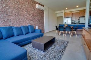 sala de estar con sofá azul y pared de ladrillo en Best Apt Luxury Modern New 2BR Gym Pool 3mins SPGG, en Monterrey
