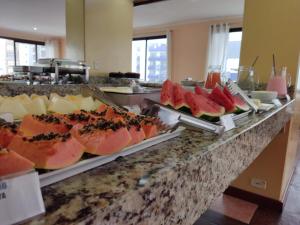 a buffet line with watermelons and cheese at De Rose Centro Hotel in Torres