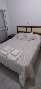 Una cama blanca con dos toallas encima. en Departamentos La Tita en Concepción del Uruguay