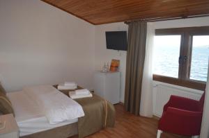 a bedroom with a bed and a window and a chair at Yakamoz Otel in Urla