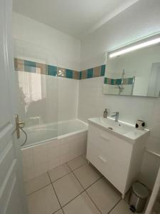 un bagno bianco con lavandino e vasca di Appartement cosy. Merville centre. Proche aéroport et Parc Exposition a Merville
