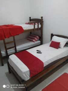 卡希亞斯公爵城的住宿－Jardim Paraíso，一间卧室配有两张双层床,铺有红白色床单。