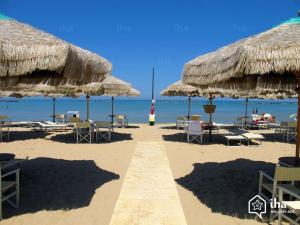 a beach with chairs and straw umbrellas and the ocean at Casa vacanza relax in Ortona