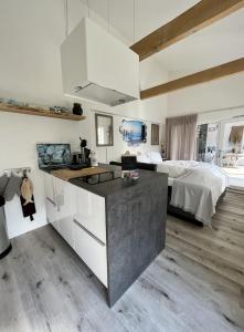 a kitchen with white cabinets and a bed in a room at Tussenrenesseenstrand in Renesse