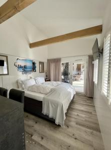 een slaapkamer met een groot bed met witte lakens bij Tussenrenesseenstrand in Renesse