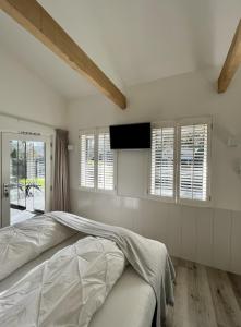 a white bedroom with a bed and windows at Tussenrenesseenstrand in Renesse