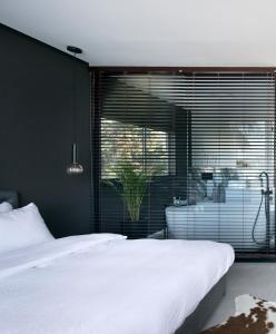 a bedroom with a white bed and a large window at Urbanica Carmel- Apartments in Haifa