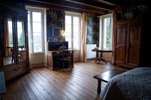 Schlafzimmer mit Holzböden und Fenstern sowie einem Schreibtisch in der Unterkunft Chambre confortable dans maison bourgeoise in Rouffignac