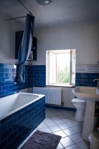 Chambre confortable dans maison bourgeoise في Rouffignac: حمام من البلاط الأزرق مع حوض استحمام ومغسلة