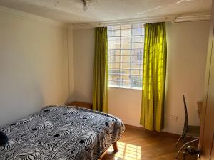 1 dormitorio con 1 cama y una ventana con cortinas verdes en Quitumbe - Moderno y cómodo departamento en Quito