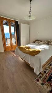 een slaapkamer met een bed en een groot raam bij Appartement lumineux au centre du village in Leysin
