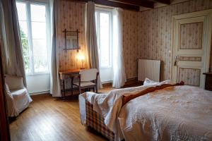 Chambre confortable dans maison bourgeoise في Rouffignac: غرفة نوم بسرير ومكتب ونوافذ