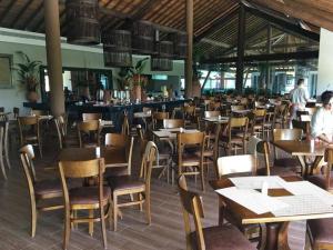 a restaurant with wooden tables and chairs and a bar at Apt. 305 Bloco 7 · Flat com 2 quartos no La Fleur Polinésia - Muro Alto in Porto De Galinhas