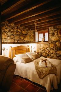 a bedroom with a large bed in a stone wall at Apartamentos Rurales La Casina del Fontan in Valle de Lago