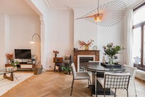 een woonkamer met een tafel en stoelen en een televisie bij Traditional chic, High Ceilings' apt Aircos and Garage in Antwerpen