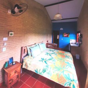 Espaço Puri في Divino de São Lourenço: غرفة نوم بسرير وجدار من الطوب