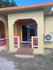 a small house with a door and a fan at GraceWay Studio Apt with A/C -3mins walk to beach in Negril