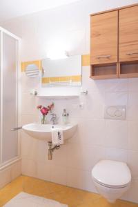 a white bathroom with a sink and a toilet at Hartlhof Urlaub am Baby- und Kinderbauernhof in Niederau