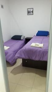 two beds in a room with purple sheets at MyR alojamiento in Ushuaia