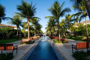 a fountain in a park with benches and palm trees at Mandara Lanai Apartamento Terreo in Aquiraz