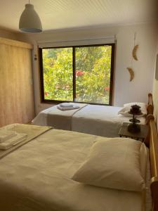 2 camas en una habitación con ventana grande en Casa Amatista Travels en Vicuña