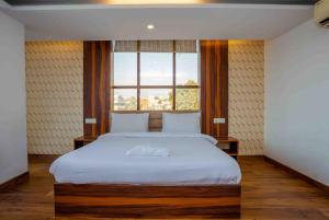 a bedroom with a large white bed with a window at HOTEL DOON in Dehradun +22 photos