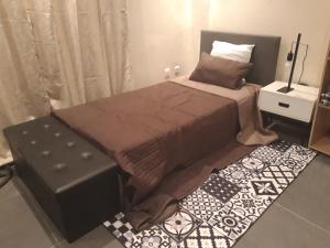 a small bedroom with a bed and a ottoman at Résidence Edelweiss in Dakar