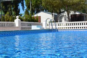 a swimming pool with a white fence and blue water at Camping Valencia el Saler in El Saler
