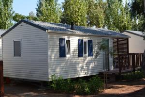 a white house with blue shutters and a porch at Camping Valencia el Saler in El Saler
