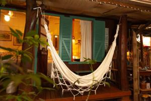 a hammock hanging from a porch of a house at Pousada das Meninas in Ilha do Mel