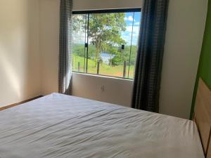 um quarto com uma cama e uma grande janela em Charme Corumbá em Alexânia