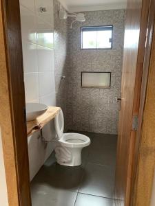 uma casa de banho com um WC, um lavatório e uma janela em Charme Corumbá em Alexânia