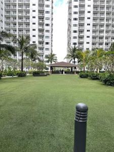 a black pole in a park with tall buildings at Shawnalyn Condo-tel at Mall of Asia Philippines in Manila