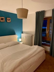 a bedroom with a white bed and a blue wall at Desiree Apartment in Folgarida