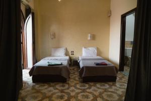 two beds in a room with two windows at Alf Leila Boutique Hotel in Dahab