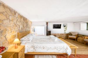 a bedroom with a large bed and a stone wall at Nativo - Nature Studio with Kitchenette and private external bathroom in Nazaré