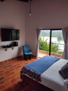 - une chambre avec un lit, une télévision et une chaise dans l'établissement La Villa, Espectaculares vistas al lago Peñol-Guatape, à Guatapé