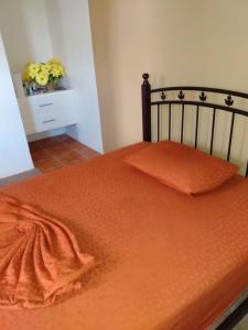 ein Bett mit einer orangefarbenen Bettdecke darüber in der Unterkunft G's Nest Bed and Breakfast in Vieux Fort