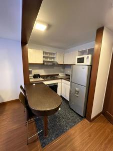 a small kitchen with a table and a refrigerator at Cómodo Apartaestudio en super ubicación in Bogotá