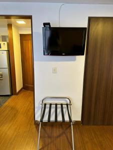 a stool in a room with a flat screen tv on a wall at Cómodo Apartaestudio en super ubicación in Bogotá