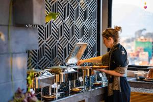 une femme debout au comptoir préparant la nourriture dans l'établissement Flock Hostel Kathmandu, à Katmandou